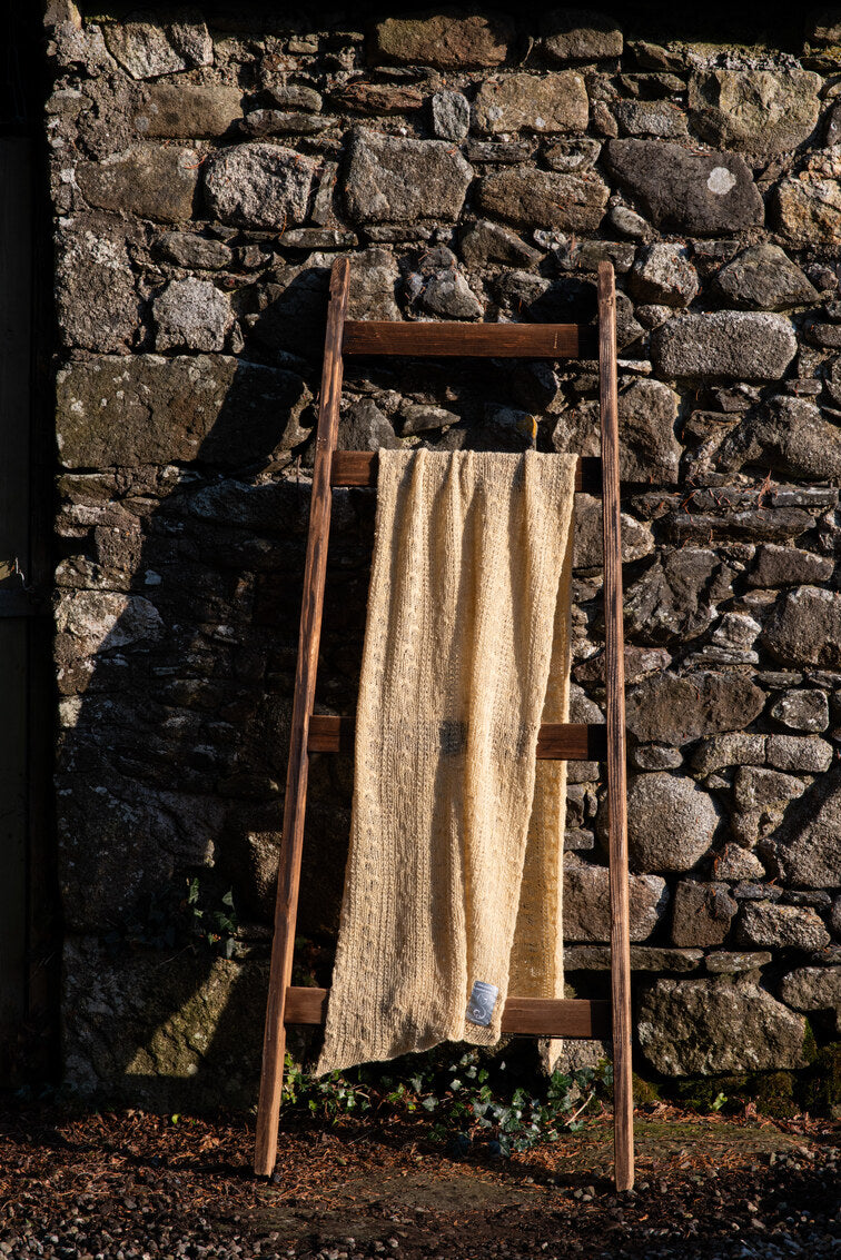 Sovereignty Shawl in Honeybee draped over ladder on a stone wall